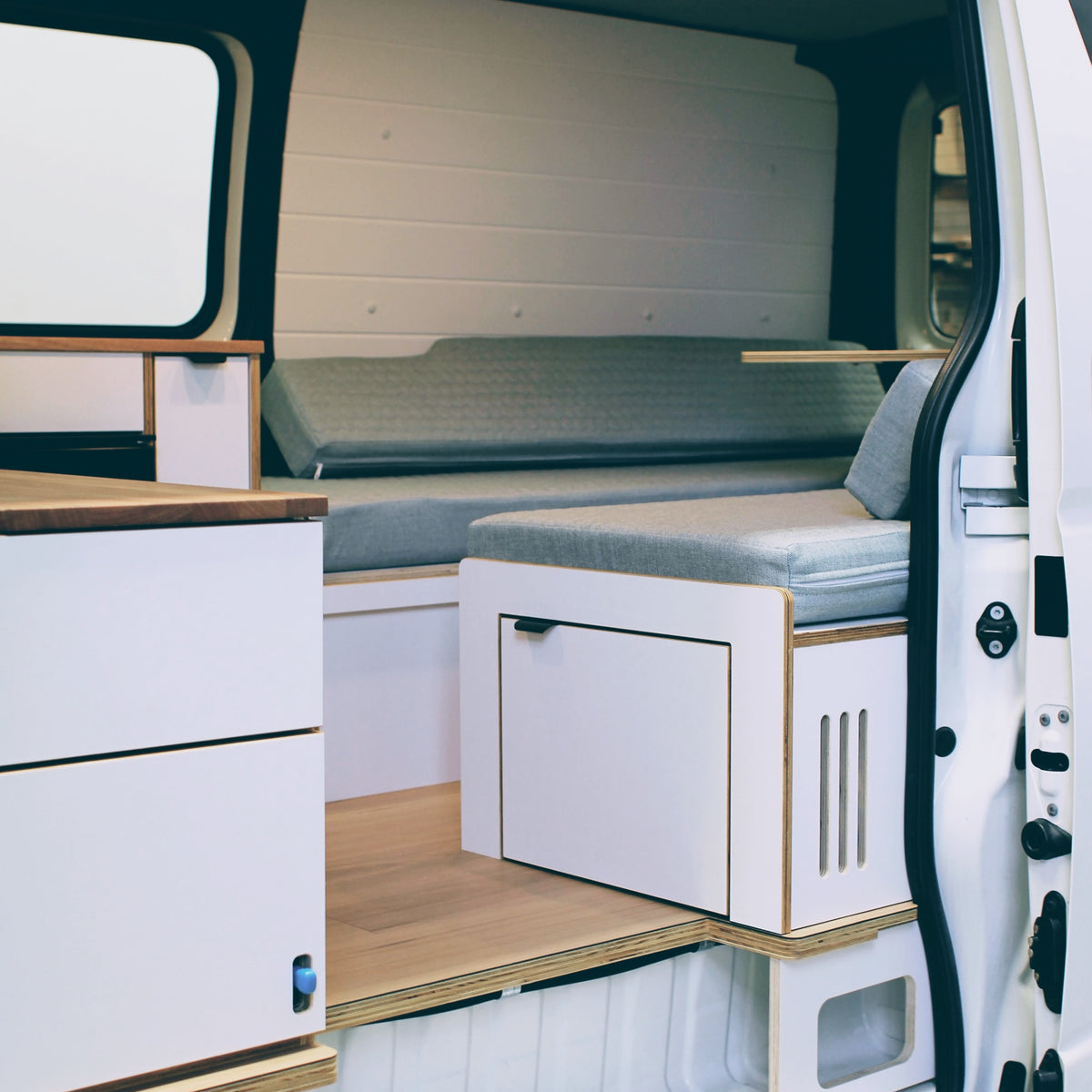 Toyota HiAce campervan interior with U-shaped lounge, kitchen and storage cabinetry